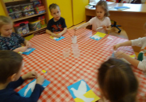 Dzieci naklejają biały szablon gołąbka.